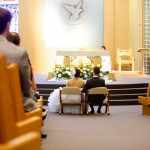 Calgary wedding photographer | Holy spirit catholic church wedding | Bride and groom sitting down in front of alter